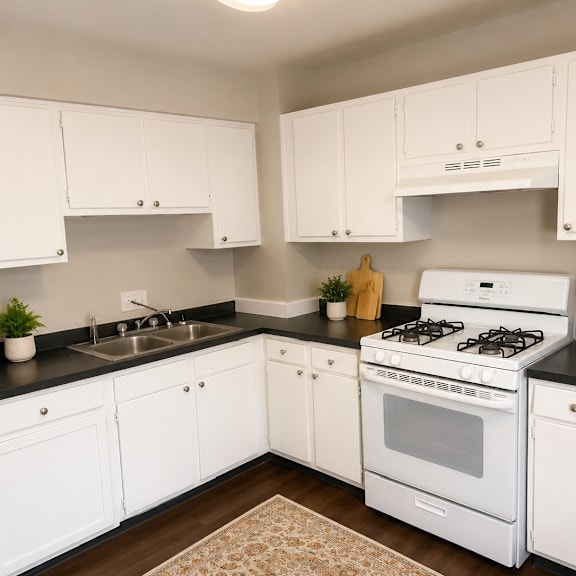 a white kitchen with black countertops and a white stove.
