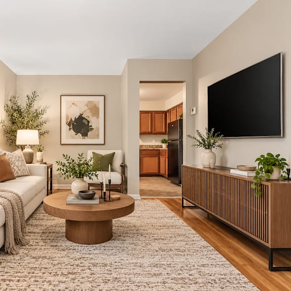 a living room with a white couch, a coffee table, and a flat screen tv mounted on the wall.