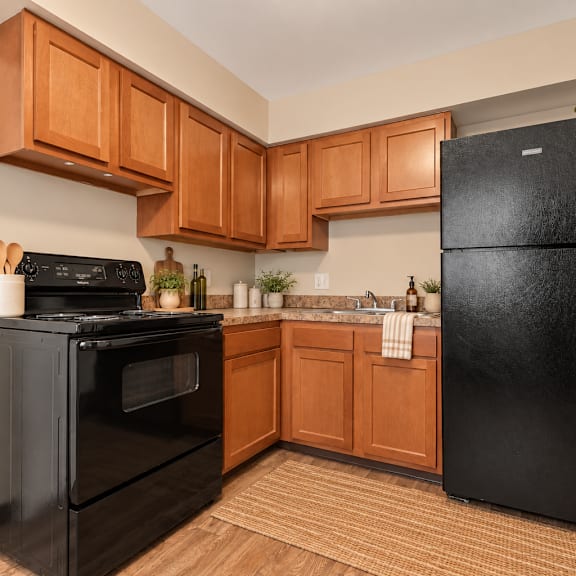 a black fridge sits in a kitchen with wooden cabinets.