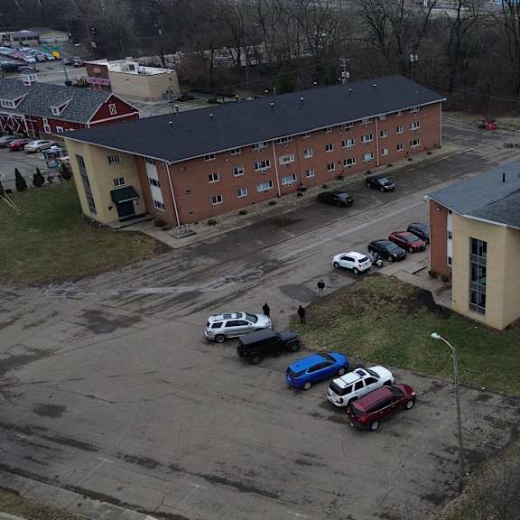 a parking lot with cars and two buildings in the background.