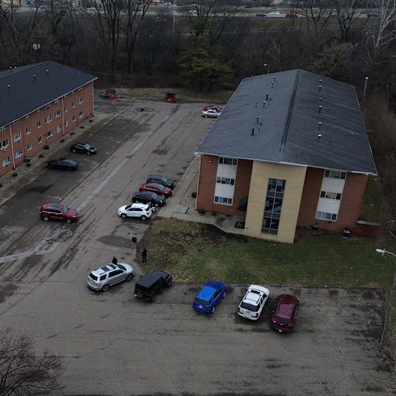 a parking lot with cars and two buildings in the background.