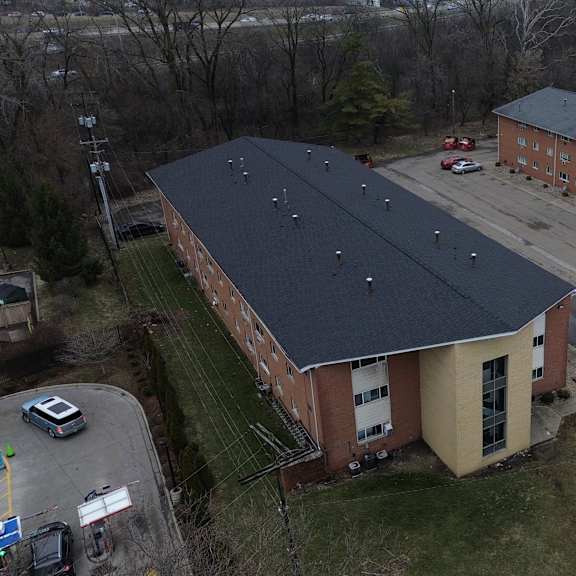 a large building with a black roof is surrounded by a parking lot.