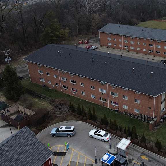 a large red brick building with a black roof and a parking lot in front.