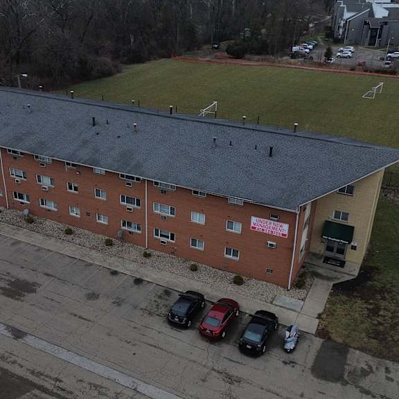 a red brick building with a black roof and a parking lot in front.