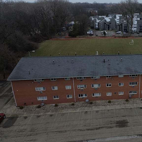a red brick building with a black roof is surrounded by a parking lot.
