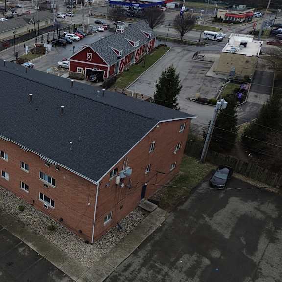 a red brick building with a black roof is surrounded by a parking lot.