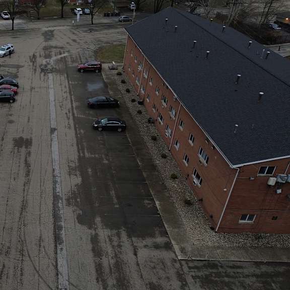 a parking lot is in the middle of two red brick buildings.