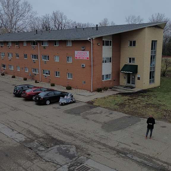 a parking lot with cars and a person standing in front of a building.