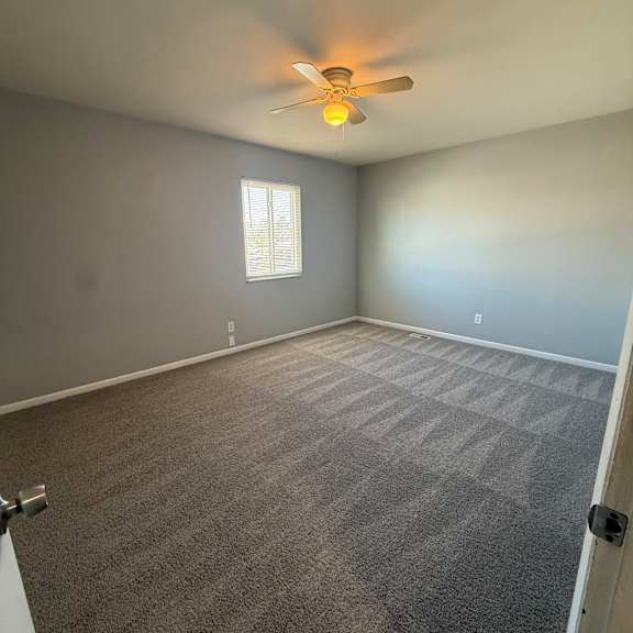 a ceiling fan with a light on in a room with a window.