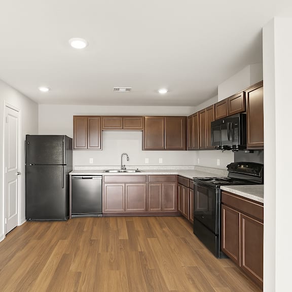 Thumbnail 2 of 3 A kitchen with wooden floors and brown cabinets.
