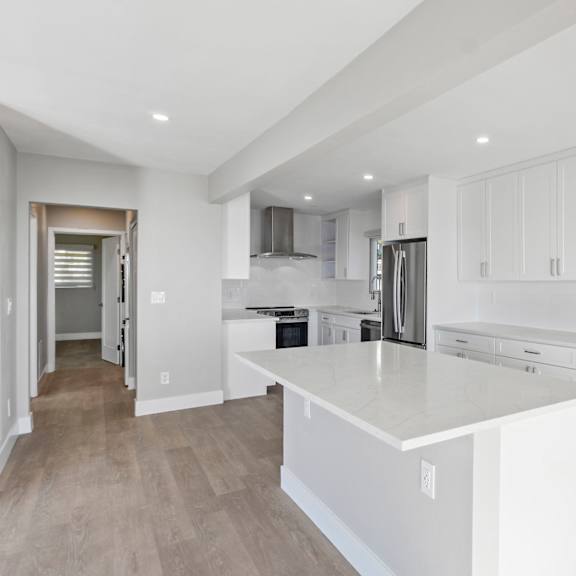 a modern kitchen with white cabinets and a large island.at ocean edge @ laguna beach, laguna beach, ca