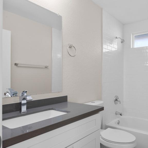 a white bathroom with a toilet, sink, and bathtub.