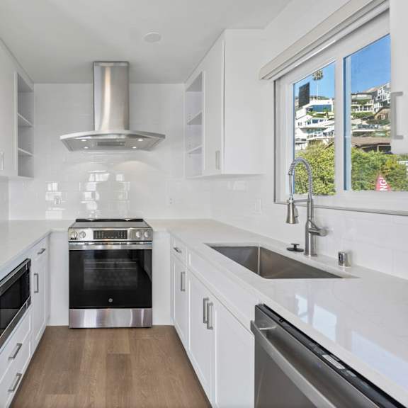 a modern kitchen with white cabinets and stainless steel appliances.at ocean edge @ laguna beach, california