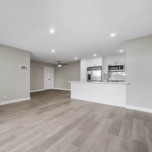 a spacious room with wooden flooring and a kitchenette in the corner at tamarack sands apartment homes, carlsbad