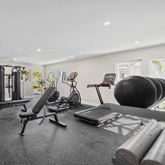 a gym with a variety of equipment including weights, a treadmill, and a stationary bike.