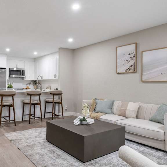 a modern kitchen with a bar area and a living room with a couch at tamarack sands apartment homes, carlsbad, california