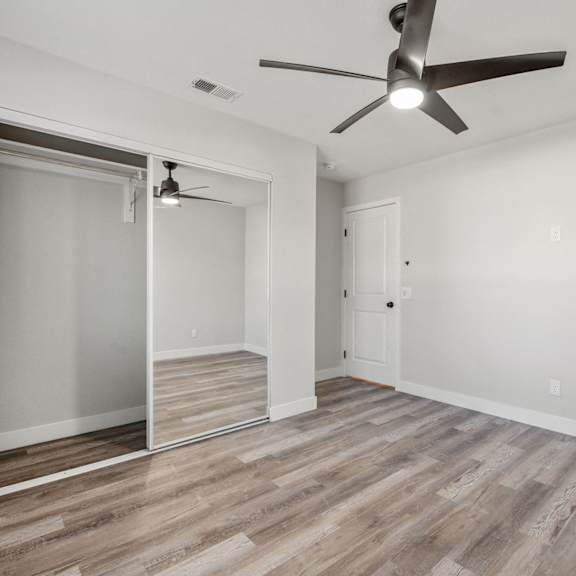 a living room with white walls and a ceiling fan