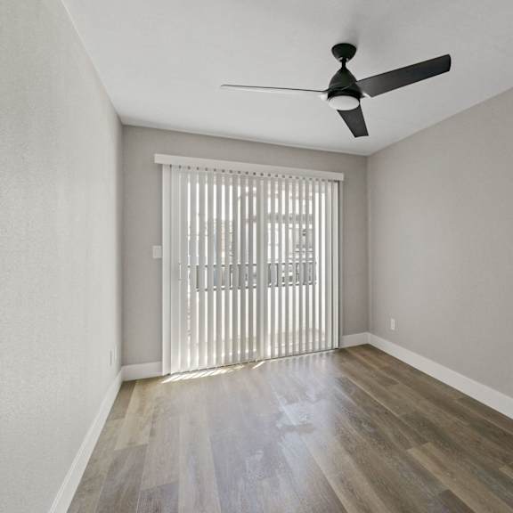 an empty living room with sliding glass doors and a ceiling fan at ocean breeze terrace apartment, huntington beach, 92648