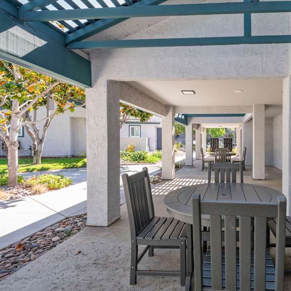 a patio with a table and chairs under a roof.