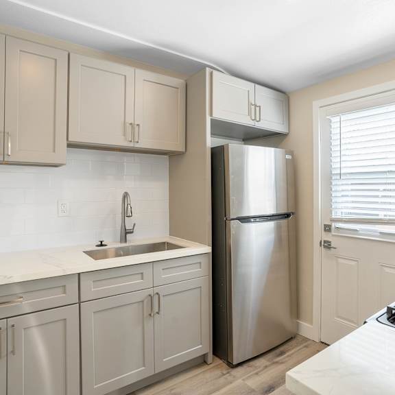 a kitchen with white cabinets and a stainless steel refrigerator at huntington manor homes apartment, huntington beach, 92648
