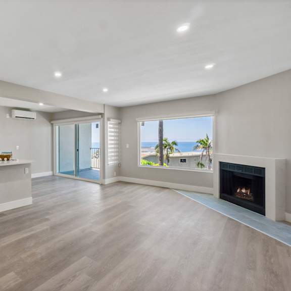 a spacious living room with a fireplace and sliding glass doors leading to a balcony.at ocean edge @ laguna beach, laguna beach, 92651