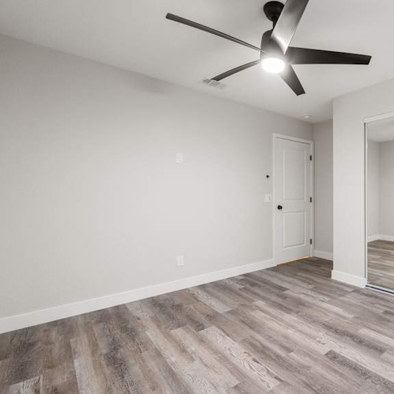 an empty living room with a ceiling fan and a sliding glass door