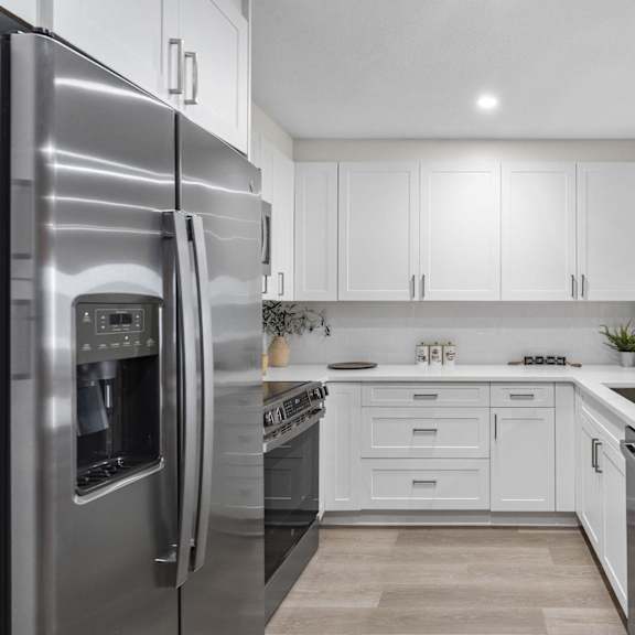 a modern kitchen with a stainless steel refrigerator and white cabinets at tamarack sands apartment homes, california