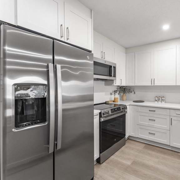 a modern kitchen with a stainless steel refrigerator and white cabinets at tamarack sands apartment homes, carlsbad, california