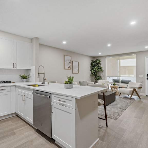 a modern kitchen with white cabinets and a wooden floor at tamarack sands apartment homes, carlsbad