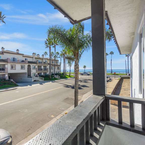 the view of the street from the balcony of an apartment building with palm trees at ocean breeze terrace apartment, huntington beach