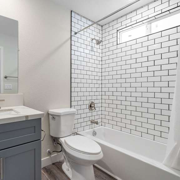 a bathroom with white subway tiles and a white sink and toilet