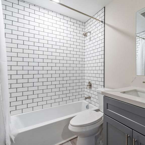 a bathroom with white tile and a sink and a toilet