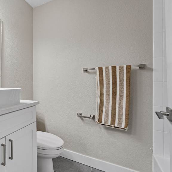 a white bathroom with a toilet, sink, and towel at tamarack sands apartment homes, california