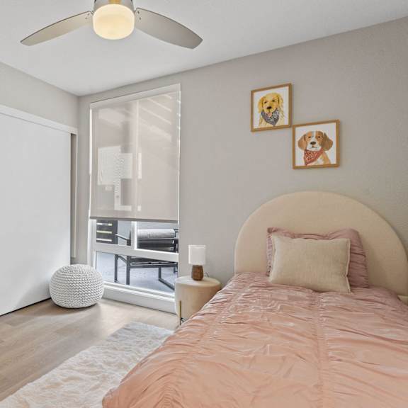 a bedroom with a bed, a ceiling fan, and a window with blinds at tamarack sands apartment homes, carlsbad
