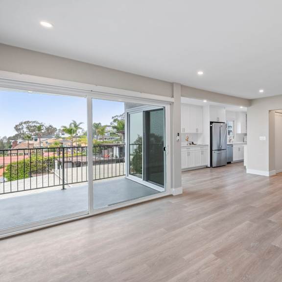 a spacious room with wooden flooring and sliding glass doors.