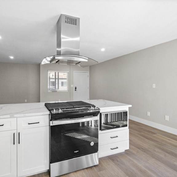 a kitchen with white cabinets and a stove and a hood at ocean breeze terrace apartment, huntington beach, ca, 92648