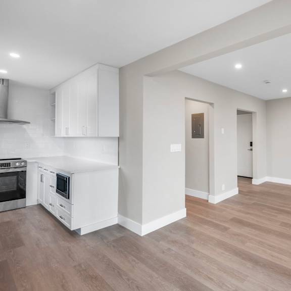 a kitchen with white cabinets and a wooden floor.