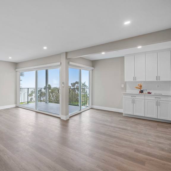 a spacious room with a sliding glass door leading to a balcony.