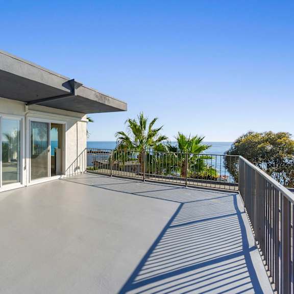 a balcony with a view of the ocean and palm trees.at ocean edge @ laguna beach, laguna beach