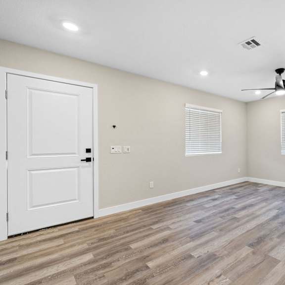 an empty living room with a ceiling fan and a door