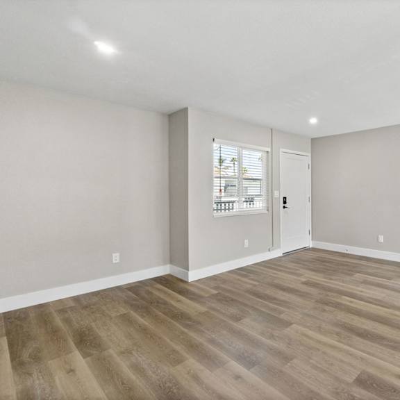 the living room of a new home with white walls and wood floors at ocean breeze terrace apartment, huntington beach, ca
