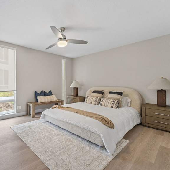 a bedroom with a large bed, a ceiling fan, and a potted plant at tamarack sands apartment homes, carlsbad