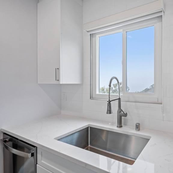 a modern kitchen with a stainless steel sink and white cabinets.