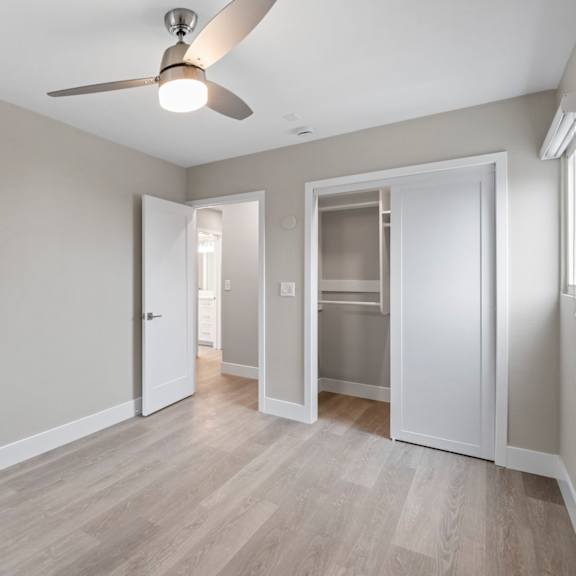 a room with a ceiling fan and a door leading to another room.