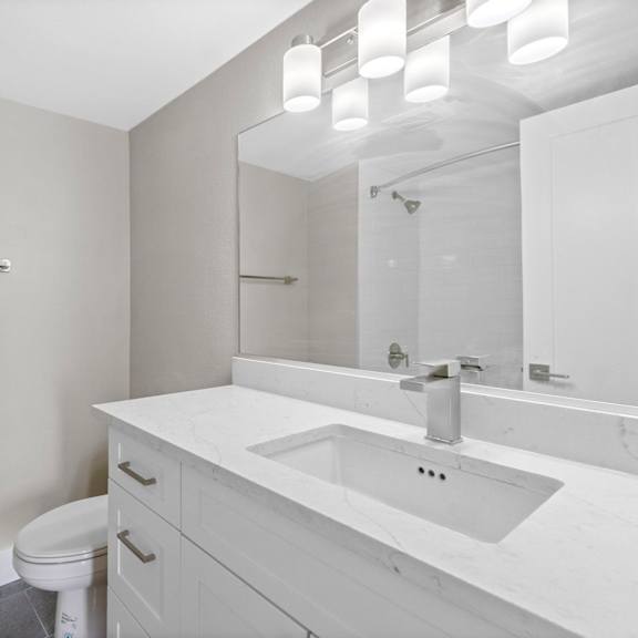 a white bathroom with a toilet, sink, and mirror.at ocean edge @ laguna beach, california