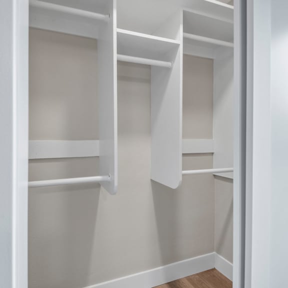 a white closet with shelves and a door open.