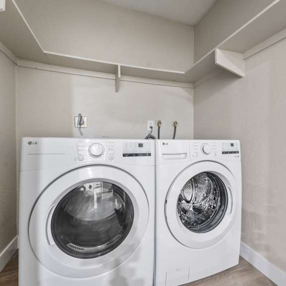 two white front loading washing machines in a laundry room at tamarack sands apartment homes, carlsbad, california