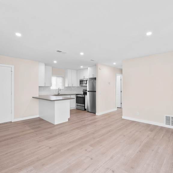 a kitchen with a white countertop and wooden flooring.