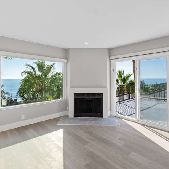 a spacious living room with a fireplace and sliding glass doors leading to a balcony.at ocean edge @ laguna beach, laguna beach, 92651
