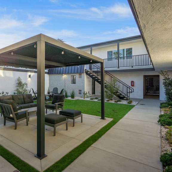 a patio with a table and chairs under a roof at ocean breeze terrace apartment, huntington beach, 92648